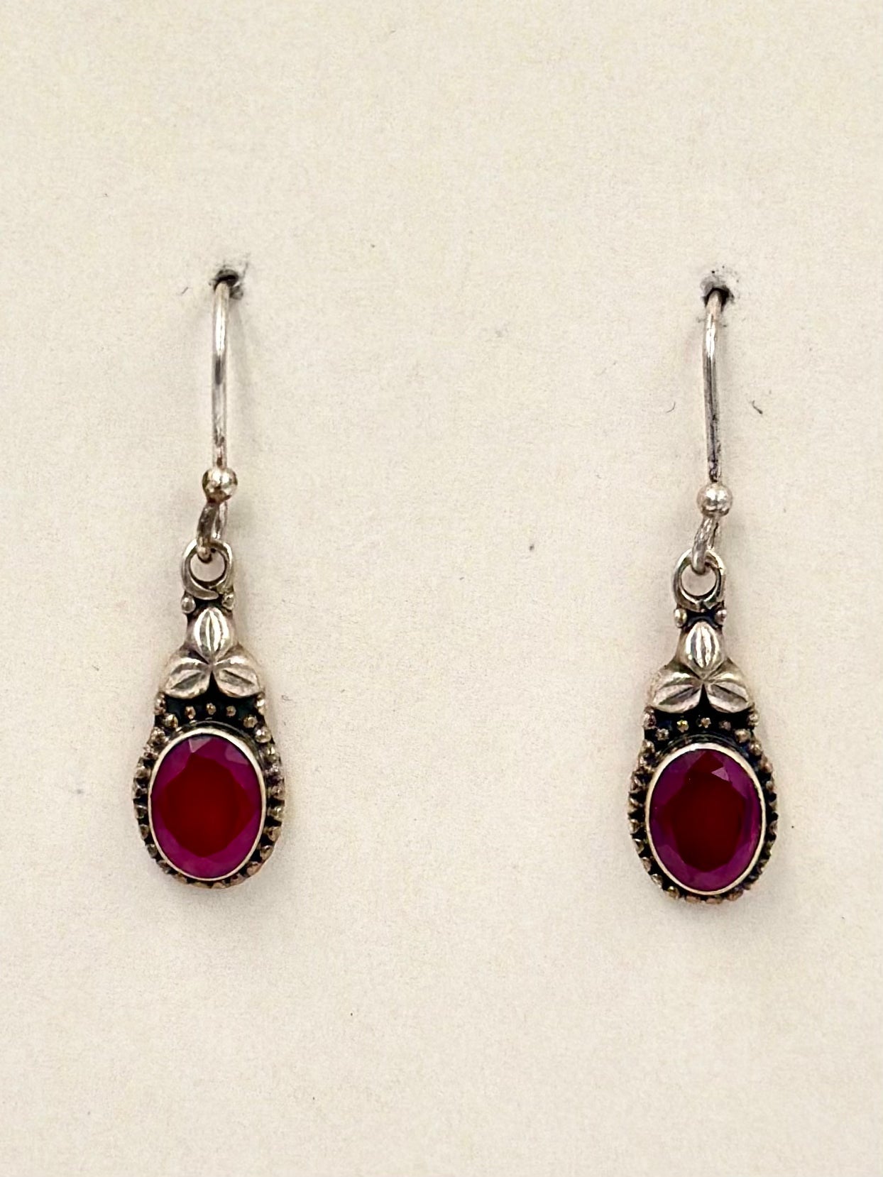 Encrusted with ruby and a small oxidised flower, sterling silver drop earrings
