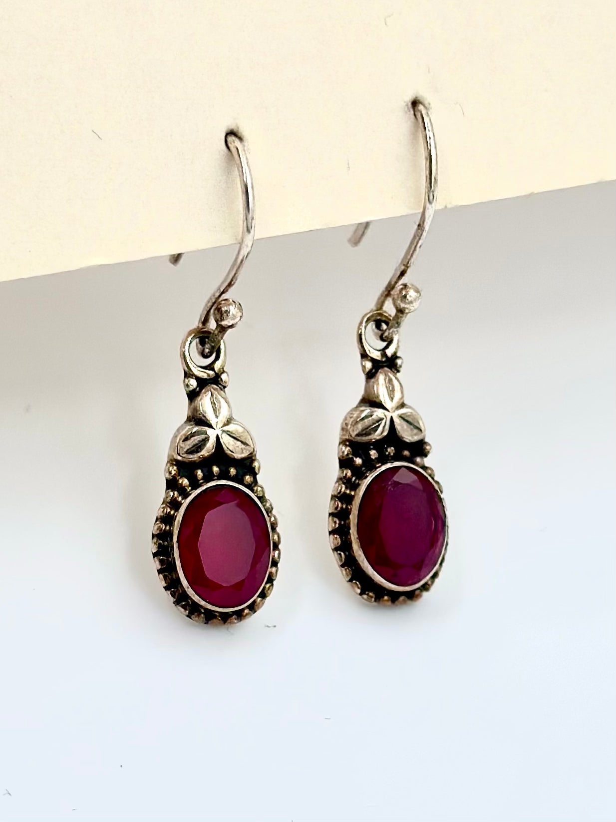 Encrusted with ruby and a small oxidised flower, sterling silver drop earrings