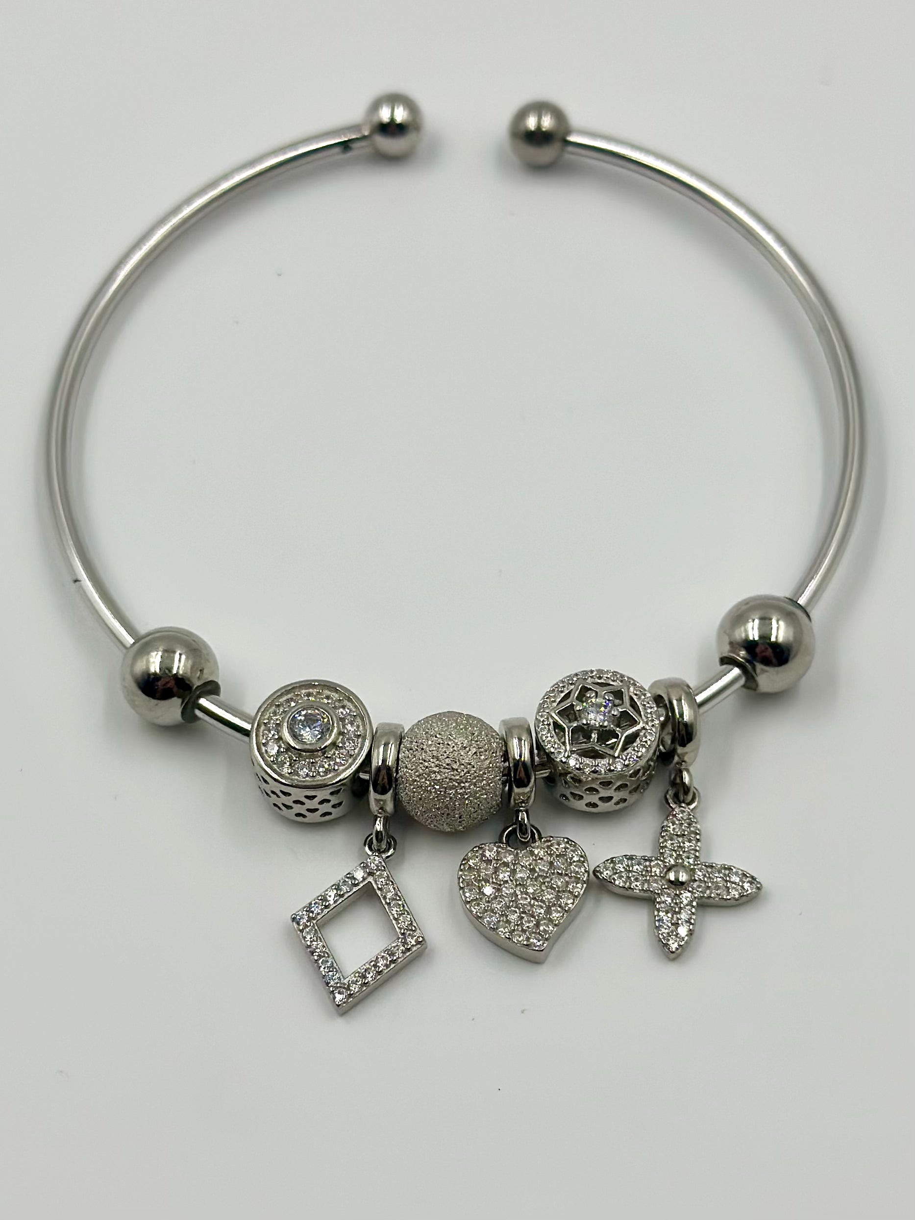 Zircon studded, many shapes sterling silver charm bracelet